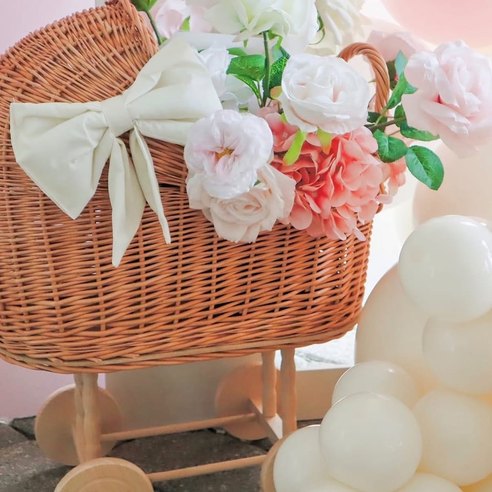 Wicker dessert cart decorated with a large white bow, pastel flowers, and white balloons.